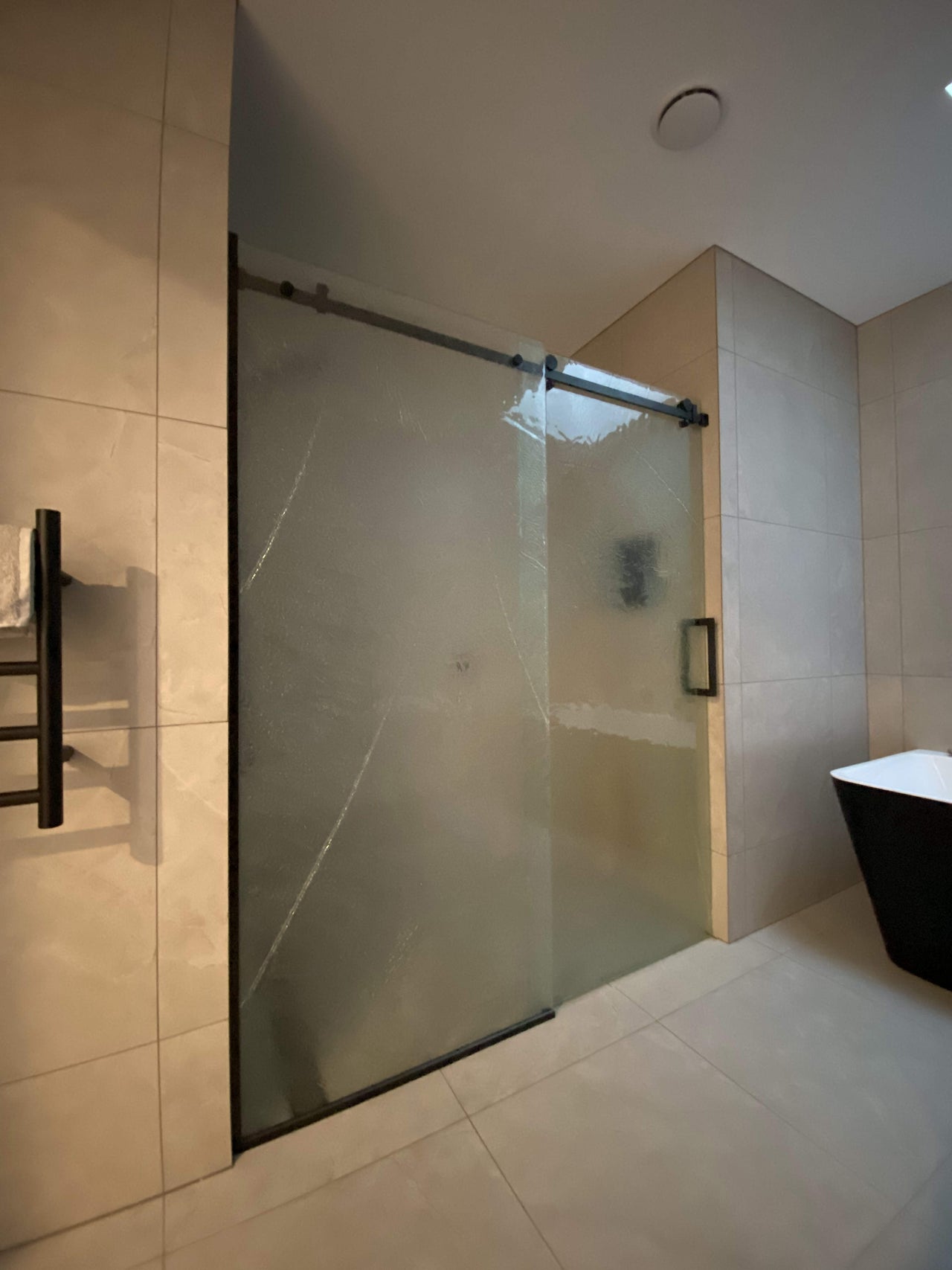 Slumped glass on black hardware for a sliding shower 